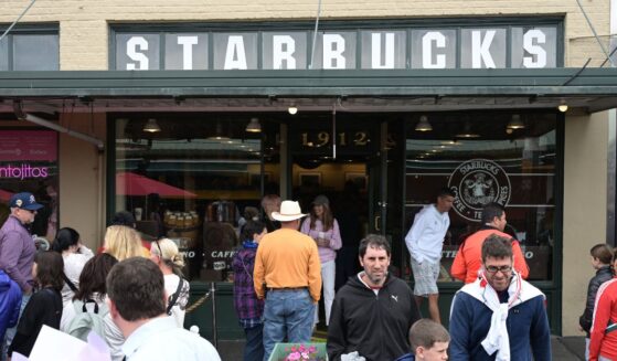 People queue outside the first coffee shop Starbucks, opened in 1971, in front of the Pike Place Market in downtown Seattle, Washington, on June 25, 2025.