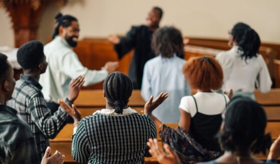 A group of churchgoers is singing and raising their hands while praying together.