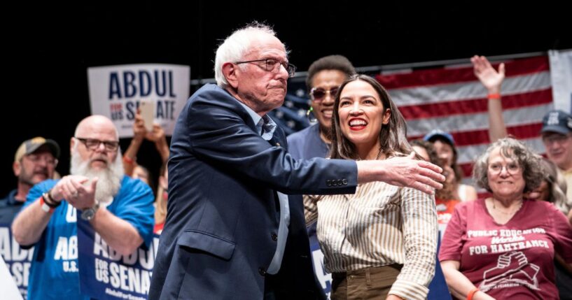 Sen. Bernie Sanders greets Rep. Alexandria Ocasio-Cortez at The People v. The Powerful rally at the Detroit Opera House on July 18, 2026, in Detroit, Michigan.