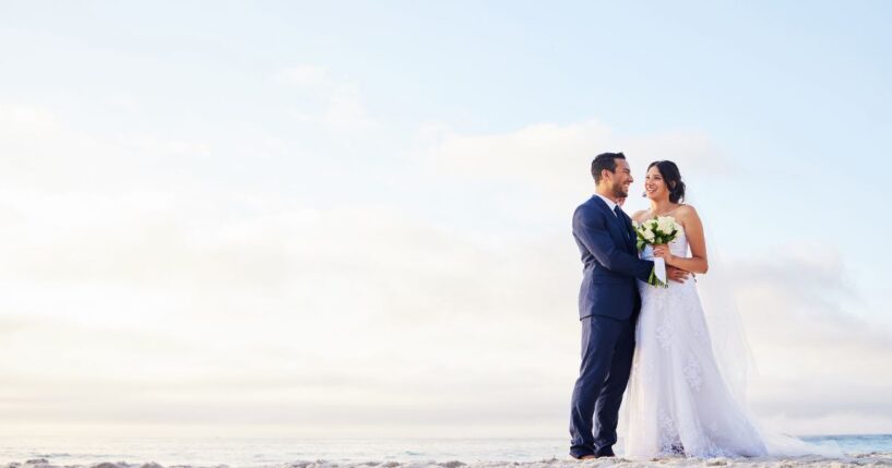 A young couple on the beach on their wedding day.