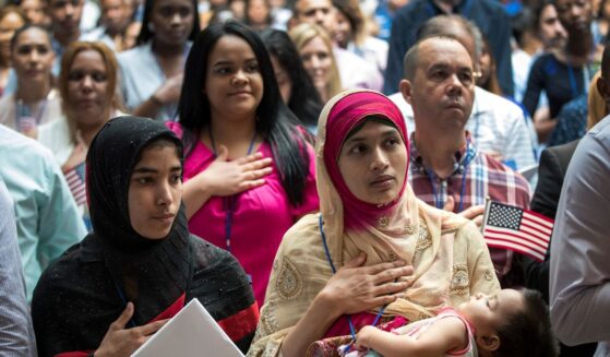 Mosammat Rasheda Akter, originally from Bangladesh, holds her 7-month-old daughter Fahmida as she recites the Pledge of Allegiance after officially becoming a U.S. citizen during a naturalization ceremony at the New York Public Library on July 3, 2018, in New York City.