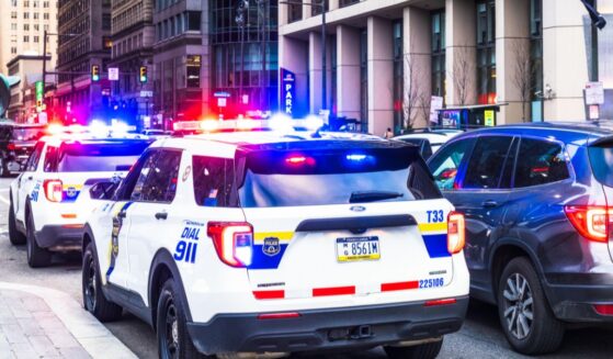Police vehicles with their lights flashing alongside traffic in downtown Philadelphia.