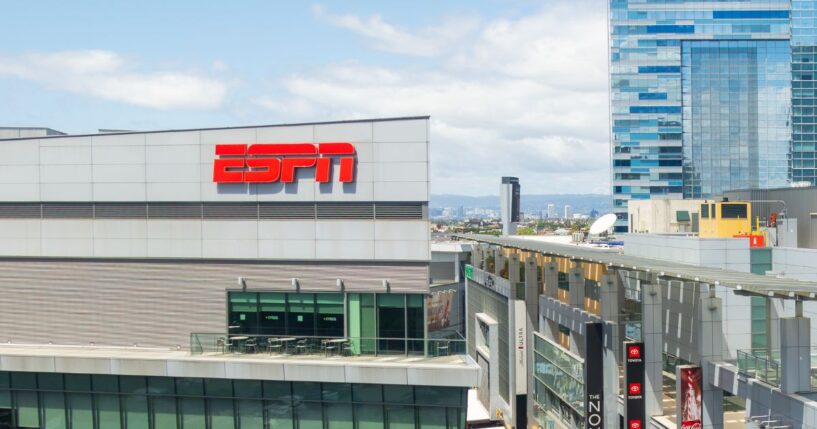 An elevated panoramic view of the L.A. Live entertainment district in Downtown Los Angeles featuring the ESPN studios, Lucky Strike, restaurants, retail stores, pedestrian walkways, and modern high-rise office towers.