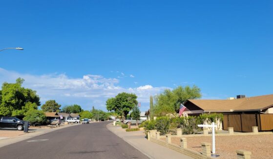 A residential street in Phoenix, Arizona, showcases single-story ranch homes and classic southwestern desert xeriscape landscaping.