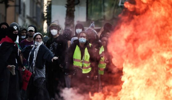 Protesters stand behind a fire during clashes prior to the start of a demonstration to protest against the "high cost of living" in Marseille, southern France, on Oct. 17, 2026.