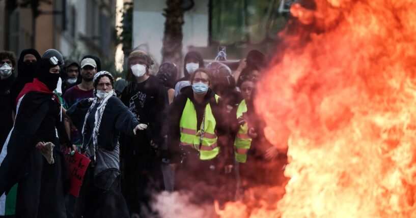 Protesters stand behind a fire during clashes prior to the start of a demonstration to protest against the "high cost of living" in Marseille, southern France, on Oct. 17, 2026.