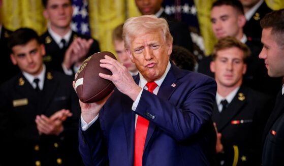 President Donald Trump holds up a football presented during a presentation ceremony for the Commander-in-Chief Trophy to the Navy Midshipmen football team in the East Room of the White House on April 15, 2025, in Washington, D.C.