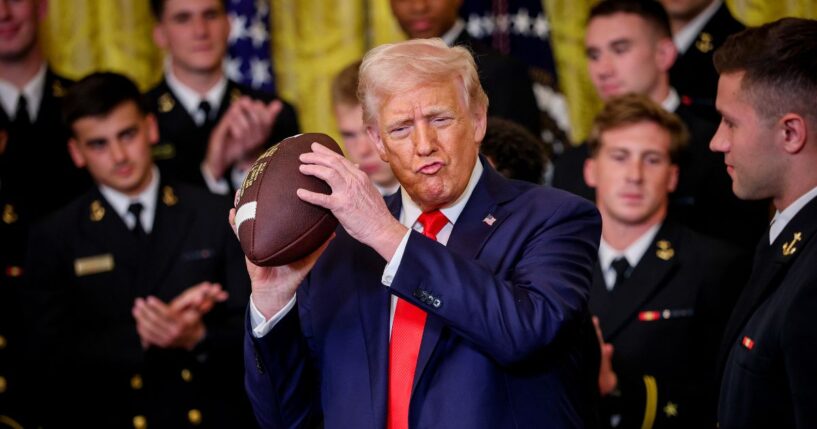 President Donald Trump holds up a football presented during a presentation ceremony for the Commander-in-Chief Trophy to the Navy Midshipmen football team in the East Room of the White House on April 15, 2025, in Washington, D.C.