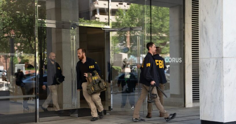FBI agents leave the office of John Bolton, former national security adviser to President Trump, with several boxes and other materials on Aug. 22, 2025, in Washington, D.C.