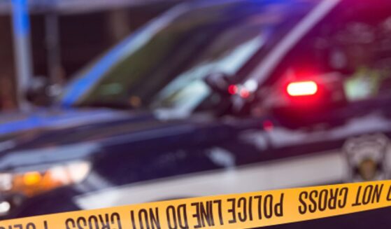A police car flashes red and blue lights behind police tape.