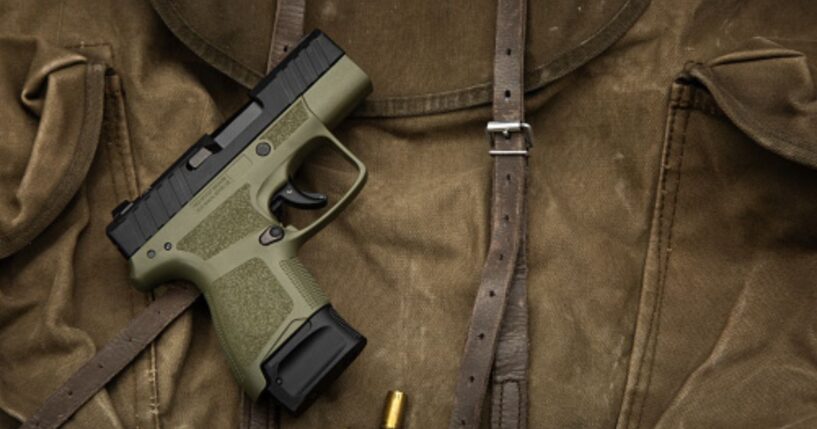 A pistol lays on a dark brown fabric.
