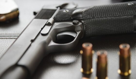 A black gun sits on a black table.