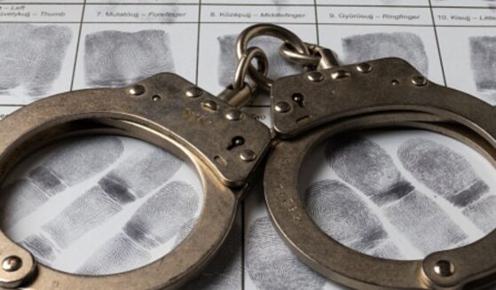 A pair of handcuffs sit on a paper of thumb prints.
