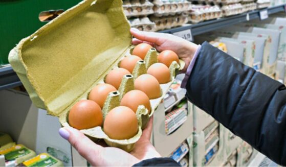 A carton of eggs open in a grocery store aisle.