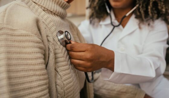 A doctor puts a stethoscope over a patient’s heart.
