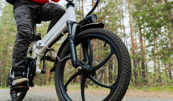 An electric bike rides along a path in the woods.