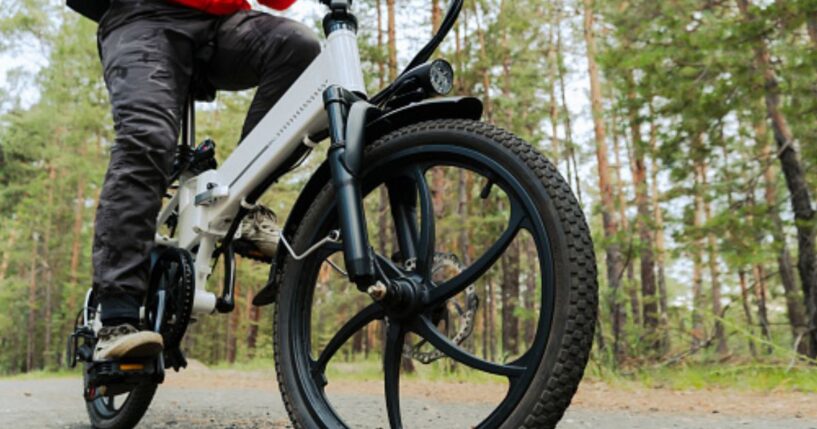 An electric bike rides along a path in the woods.