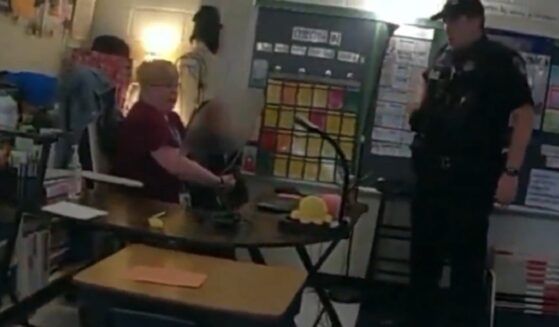 A police officer interviews a teacher holding a 6-year-old who just shot another teacher in Richneck, Virginia, in 2023.